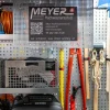 Lagerraum mit Seilen, orange Kabel, Schaufeln, Meyer Hochwasserschutz-Equipment und Infoschild mit QR-Code und Kontaktdaten.